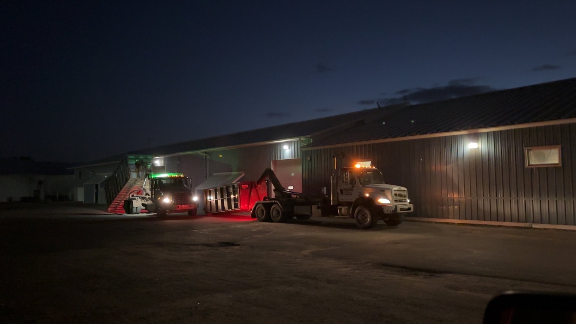 Roll-off trucks at the shop at dusk